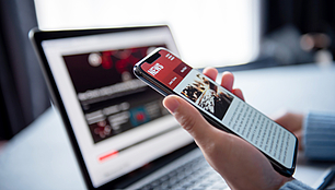 Company News and Press Releases Smartphone and laptop show digital news content for company updates, press releases and publications.