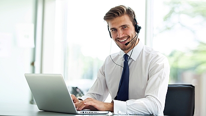Trainer with headset and laptop representing online seminars and digital training.