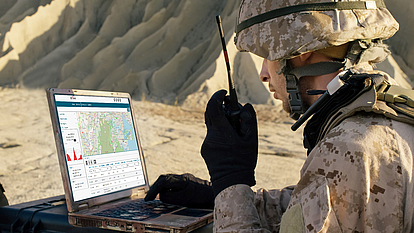 mySPECTRA for Defense Mission Planning Soldier using a laptop in the field for automated spectrum management and defense mission planning.